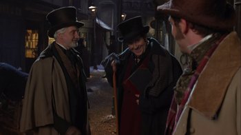 Movie still from “A Christmas Carol” (1999), directed by David Hugh Jones – A group of people standing next to each other on a street; Medium shot, Over the shoulder angle