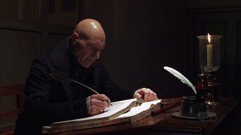 Movie still from “A Christmas Carol” (1999), directed by David Hugh Jones – A bald man sitting at a desk writing on a piece of paper; Medium shot, Low angle