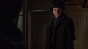 Movie still from “A Christmas Carol” (1999), directed by David Hugh Jones – An older man wearing a black coat and a black hat; Close Up shot, Over the shoulder angle