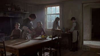 Movie still from “A Christmas Carol” (1999), directed by David Hugh Jones – A group of people standing around a table in a room; Wide shot, Low angle
