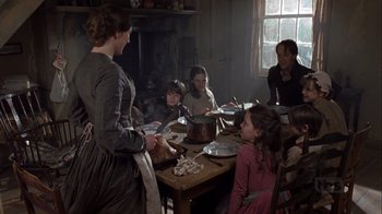Movie still from “A Christmas Carol” (1999), directed by David Hugh Jones – A group of people sitting around a table with food; Medium shot, High angle