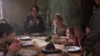 Movie still from “A Christmas Carol” (1999), directed by David Hugh Jones – A group of people sitting at a table with plates; Medium shot, High angle
