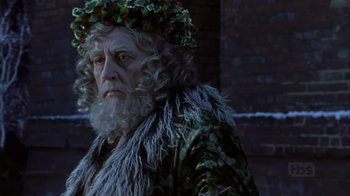 Movie still from “A Christmas Carol” (1999), directed by David Hugh Jones – An old man with a wreath on his head; Close Up shot, Over the shoulder angle
