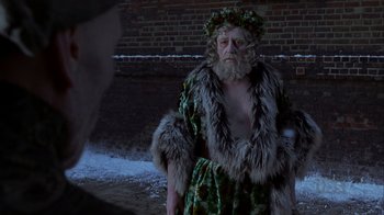 Movie still from “A Christmas Carol” (1999), directed by David Hugh Jones – A man dressed as santa claus standing in front of a brick wall; Medium shot, Over the shoulder angle