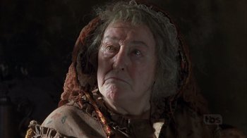 Movie still from “A Christmas Carol” (1999), directed by David Hugh Jones – An old woman wearing a hood with a sad look on her face; Close Up shot, Low angle