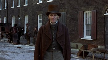 Movie still from “A Christmas Carol” (1999), directed by David Hugh Jones – A man wearing a brown coat and a brown hat; Medium shot, Low angle