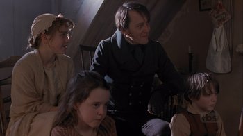 Movie still from “A Christmas Carol” (1999), directed by David Hugh Jones – A group of people sitting in a room; Medium shot, Over the shoulder angle