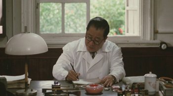 Movie still from “A City of Sadness” (1989), directed by Hsiao-Hsien Hou – A man sitting at a table writing on a piece of paper; Medium shot, Low angle