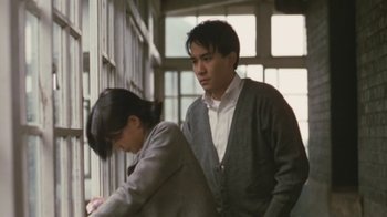 Movie still from “A City of Sadness” (1989), directed by Hsiao-Hsien Hou – A man and a woman standing next to each other in front of a window; Medium shot, Low angle