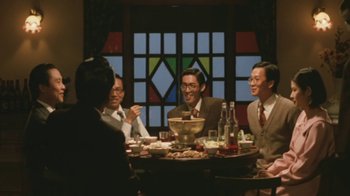 Movie still from “A City of Sadness” (1989), directed by Hsiao-Hsien Hou – A group of people sitting at a table with food; Medium shot, Low angle
