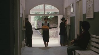 Movie still from “A City of Sadness” (1989), directed by Hsiao-Hsien Hou – A woman in a black dress holding an orange bag; Wide shot, Low angle