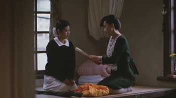 Movie still from “A City of Sadness” (1989), directed by Hsiao-Hsien Hou – Two women sitting on the ground in front of a window; Medium shot, High angle