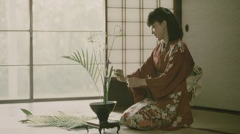 Movie still from “A City of Sadness” (1989), directed by Hsiao-Hsien Hou – A woman sitting on the ground in front of a plant; Medium shot, Low angle
