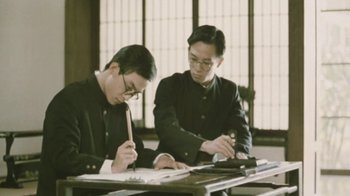 Movie still from “A City of Sadness” (1989), directed by Hsiao-Hsien Hou – Two men sitting at a table working on papers; Medium shot, Low angle