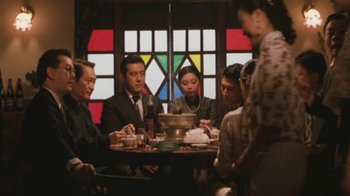 Movie still from “A City of Sadness” (1989), directed by Hsiao-Hsien Hou – A group of people sitting around a table with food; Medium shot, High angle