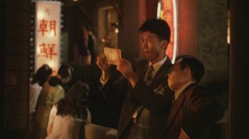 Movie still from “A City of Sadness” (1989), directed by Hsiao-Hsien Hou – A man in a suit and tie holding a camera; Medium shot, Low angle