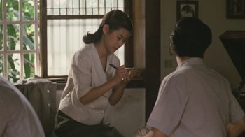 Movie still from “A City of Sadness” (1989), directed by Hsiao-Hsien Hou – A woman is holding a pen and a cell phone; Medium shot, High angle