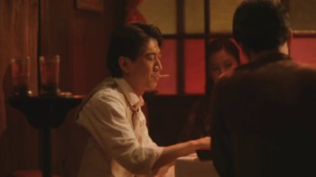 Movie still from “A City of Sadness” (1989), directed by Hsiao-Hsien Hou – A man sitting at a table with a cigarette in his mouth; Medium shot, Low angle