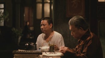 Movie still from “A City of Sadness” (1989), directed by Hsiao-Hsien Hou – Two men sitting at a table with a cup of tea; Medium shot, Over the shoulder angle