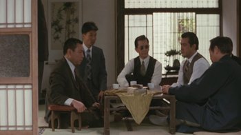 Movie still from “A City of Sadness” (1989), directed by Hsiao-Hsien Hou – A group of men sitting around a table with cups of coffee; Wide shot, High angle