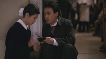Movie still from “A City of Sadness” (1989), directed by Hsiao-Hsien Hou – A man and a woman sitting on the ground looking at a cell phone; Medium shot, High angle