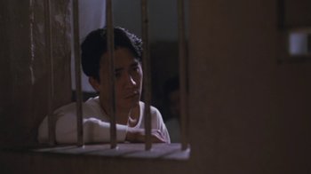 Movie still from “A City of Sadness” (1989), directed by Hsiao-Hsien Hou – A man sitting behind bars looking out of a window; Close Up shot, Low angle