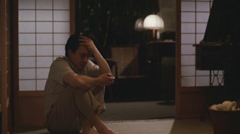Movie still from “A City of Sadness” (1989), directed by Hsiao-Hsien Hou – A man sitting on the ground in a room; Medium shot, Low angle