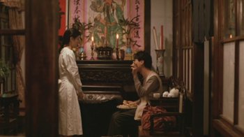 Movie still from “A City of Sadness” (1989), directed by Hsiao-Hsien Hou – A woman standing next to a man in front of a piano; Wide shot, Over the shoulder angle