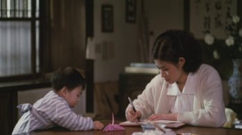 Movie still from “A City of Sadness” (1989), directed by Hsiao-Hsien Hou – A woman and a child sitting at a table writing; Medium shot, Over the shoulder angle