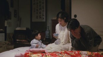 Movie still from “A City of Sadness” (1989), directed by Hsiao-Hsien Hou – A woman and two men sitting on a bed with a child; Medium shot, High angle