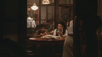 Movie still from “A City of Sadness” (1989), directed by Hsiao-Hsien Hou – Two men sitting at a table in front of a plate of food; Wide shot, High angle