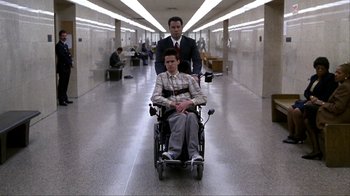 Movie still from “A Civil Action” (1998), directed by Steven Zaillian – A man in a wheel chair with a man in a suit in the background; Wide shot, Low angle