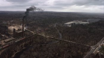 Movie still from “A Civil Action” (1998), directed by Steven Zaillian – An aerial view of a forest with smoke coming out of the chimney; Extreme Wide shot, High angle