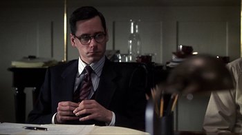 Movie still from “A Civil Action” (1998), directed by Steven Zaillian – A man sitting at a table in front of a glass of water; Close Up shot, Over the shoulder angle