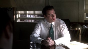 Movie still from “A Civil Action” (1998), directed by Steven Zaillian – A man sitting at a table with his hands crossed; Medium shot, Low angle