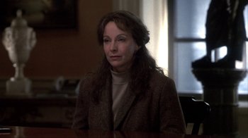 Movie still from “A Civil Action” (1998), directed by Steven Zaillian – A woman in a brown jacket is sitting in a room; Close Up shot, Over the shoulder angle