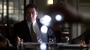 Movie still from “A Civil Action” (1998), directed by Steven Zaillian – A man sitting at a table in front of papers; Medium shot, Over the shoulder angle
