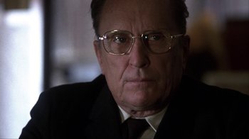 Movie still from “A Civil Action” (1998), directed by Steven Zaillian – An older man wearing glasses and a suit and tie; Close Up shot, Over the shoulder angle