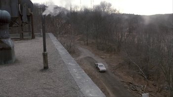 Movie still from “A Civil Action” (1998), directed by Steven Zaillian – A car driving down a dirt road next to trees; Extreme Wide shot, High angle
