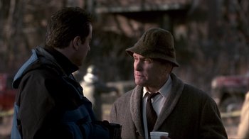Movie still from “A Civil Action” (1998), directed by Steven Zaillian – A man wearing a hat talking to another man holding a coffee cup; Medium shot, Over the shoulder angle