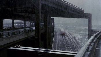 Movie still from “A Civil Action” (1998), directed by Steven Zaillian – A train traveling down train tracks under a bridge; Extreme Wide shot, High angle