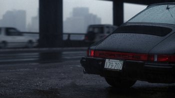 Movie still from “A Civil Action” (1998), directed by Steven Zaillian – The back end of a car on a rainy day; Wide shot, High angle