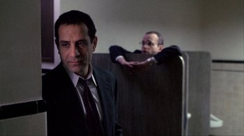 Movie still from “A Civil Action” (1998), directed by Steven Zaillian – A man wearing a suit and tie standing next to another man in a suit; Medium shot, Over the shoulder angle