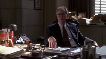 Movie still from “A Civil Action” (1998), directed by Steven Zaillian – An older man sitting at a desk in front of papers; Medium shot, Low angle