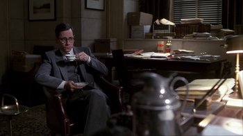 Movie still from “A Civil Action” (1998), directed by Steven Zaillian – A man sitting at a table drinking coffee; Medium shot, Over the shoulder angle