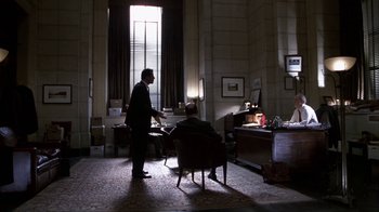 Movie still from “A Civil Action” (1998), directed by Steven Zaillian – A man in a suit standing in front of another man in a chair; Wide shot, Low angle