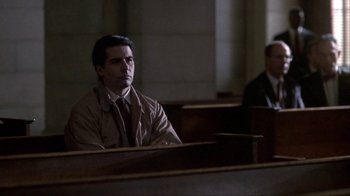 Movie still from “A Civil Action” (1998), directed by Steven Zaillian – A man sitting in front of two other men in a courtroom; Medium shot, Over the shoulder angle
