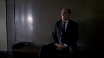 Movie still from “A Civil Action” (1998), directed by Steven Zaillian – A man in a suit and tie sitting on a bench; Medium shot, Low angle