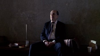 Movie still from “A Civil Action” (1998), directed by Steven Zaillian – A man in a suit and tie sitting on a bench; Medium shot, Low angle