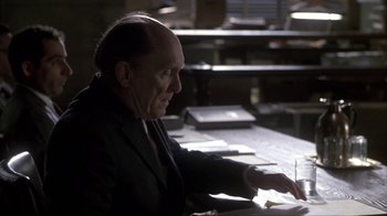 Movie still from “A Civil Action” (1998), directed by Steven Zaillian – An older man sitting at a table writing on a piece of paper; Medium shot, High angle